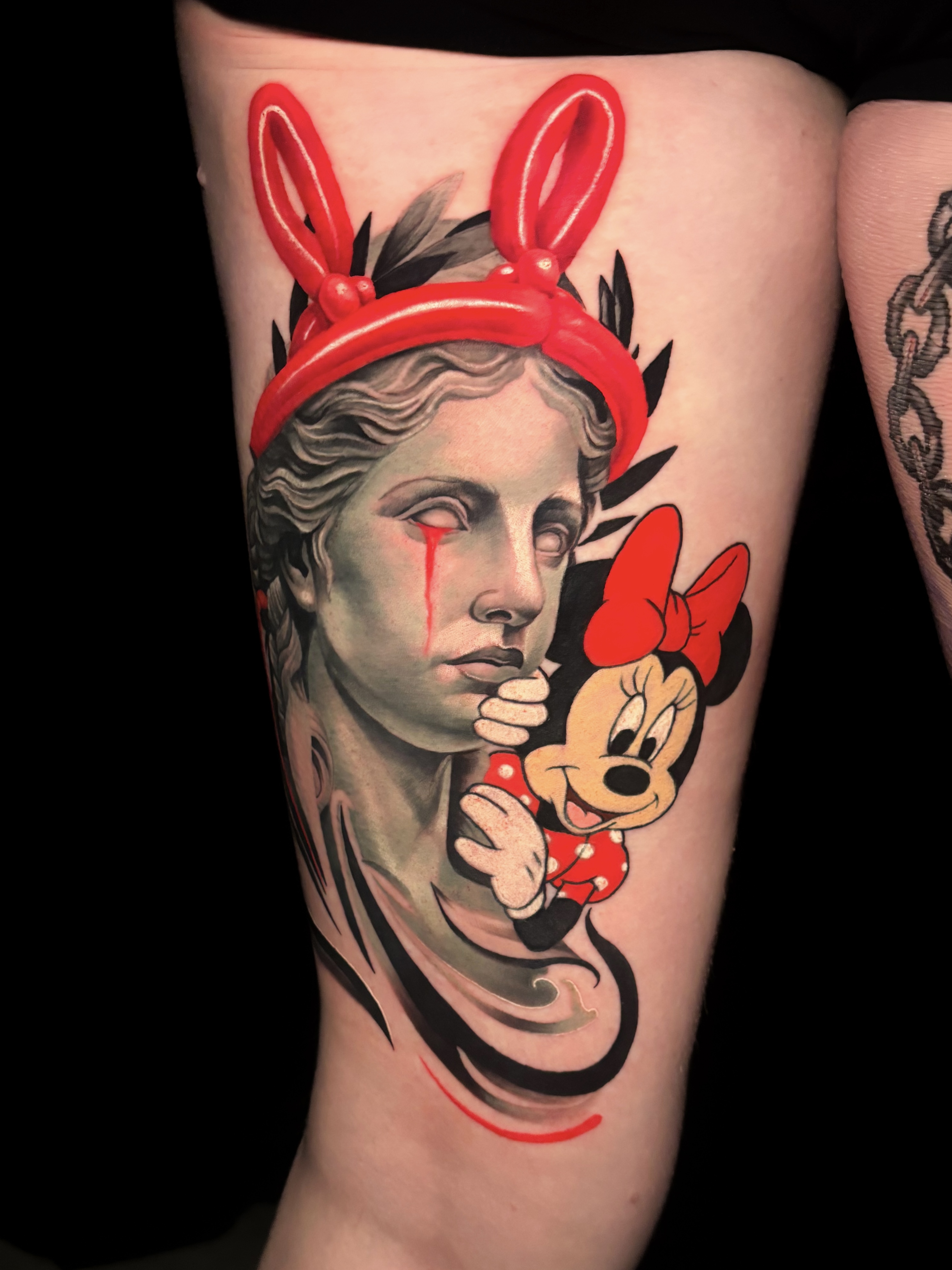 Classical statue with balloon bunny ears and Minnie Mouse tattoo