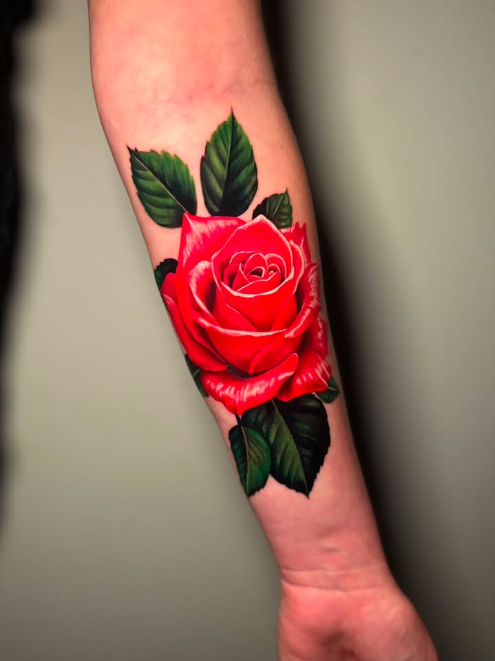Vibrant red realism rose forearm tattoo