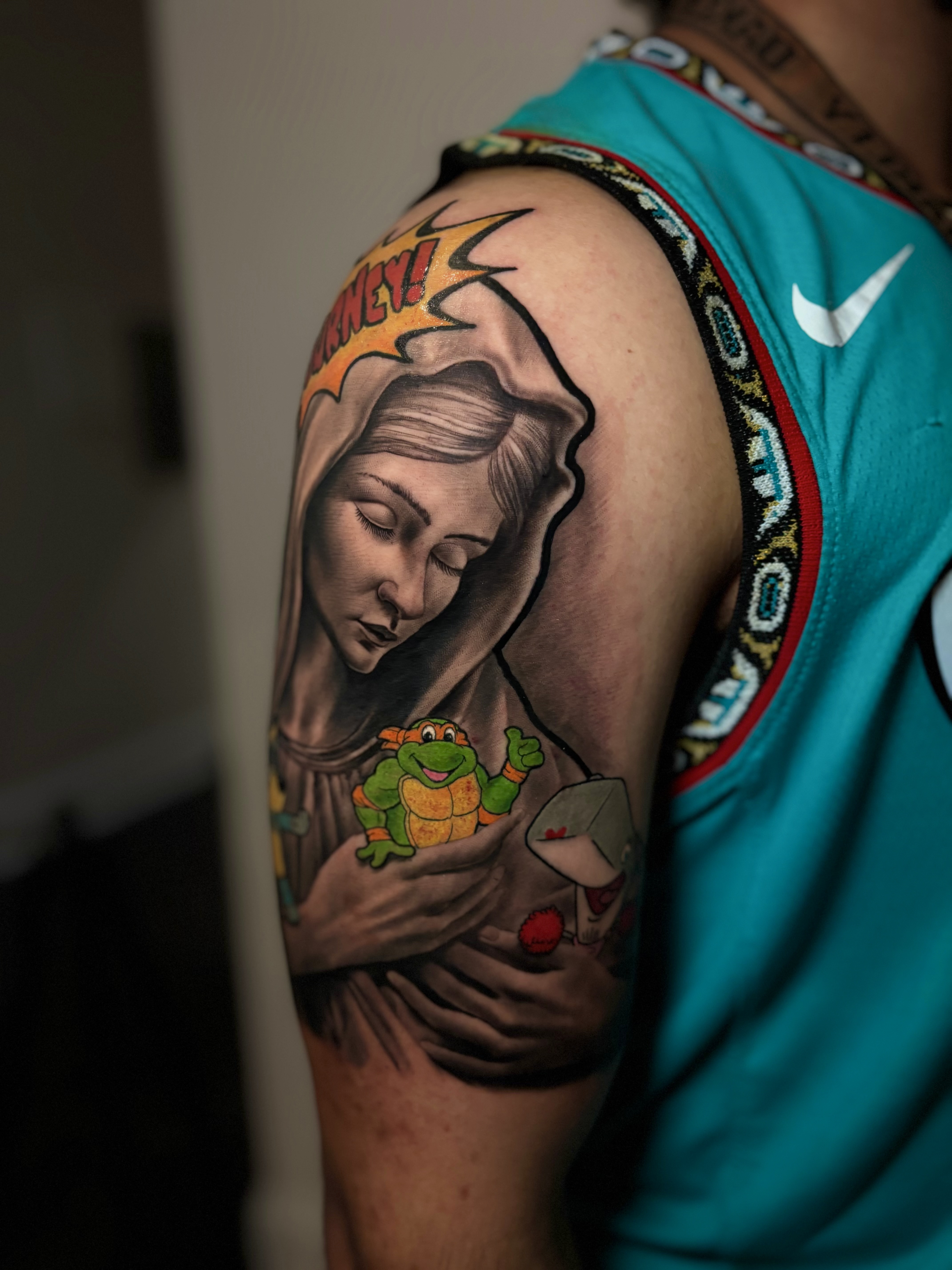 Religious figure with comic text and Ninja Turtle tattoo